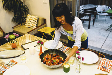 Woman placing dish on dining table - ISF01486