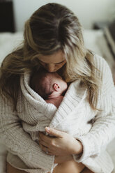 Mid adult woman kissing new born baby daughter wrapped in cardigan - ISF01494