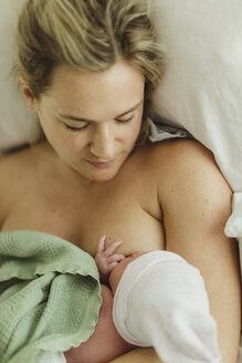 Draufsicht auf eine erwachsene Frau, die ihre neugeborene Tochter im Bett stillt - ISF01498