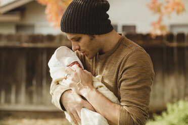 Mittlerer erwachsener Mann, der seine neugeborene Tochter im Garten betrachtet - ISF01501