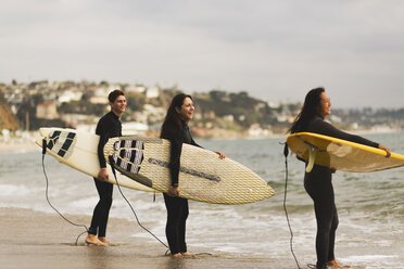 Drei Freunde stehen im Meer, halten Surfbretter und bereiten sich auf das Surfen vor - ISF01508