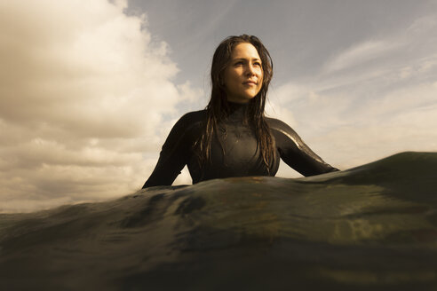Junge Frau im Meer, auf dem Surfbrett sitzend, paddelnd - ISF01513