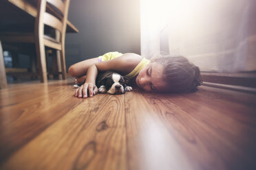 Girl lying on floor with sleeping Boston Terrier puppy - ISF01518