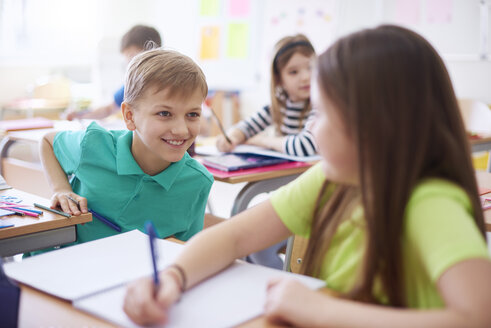 Schuljunge lächelt Schulmädchen in der Klasse an - ABIF00367