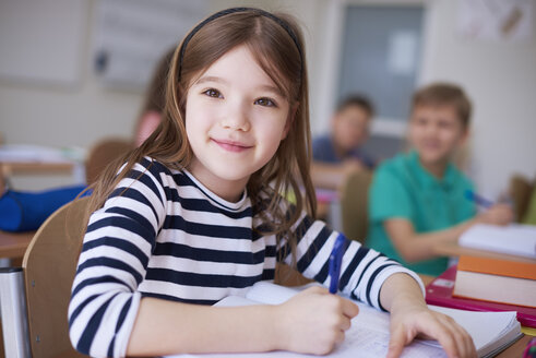 Porträt einer lächelnden Schülerin, die in der Klasse in ein Heft schreibt - ABIF00371