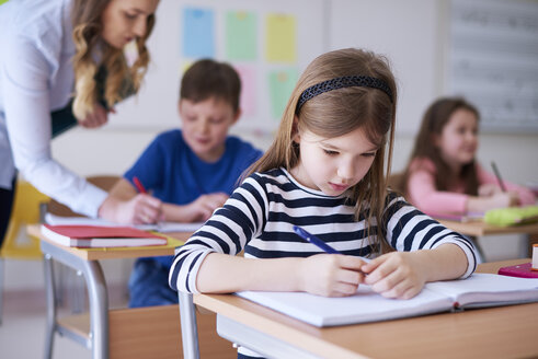 Schoolgirl writing in exercise book in class - ABIF00372