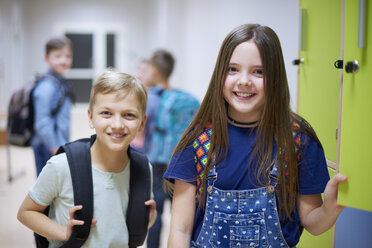 Porträt eines lächelnden Schülers und einer lächelnden Schülerin an den Schließfächern in der Schule - ABIF00376