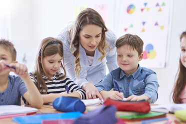 Teacher helping pupils with their tasks in class - ABIF00379