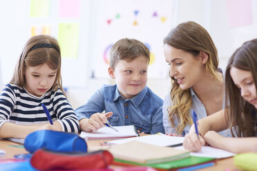 Teacher helping pupils with their tasks in class - ABIF00380