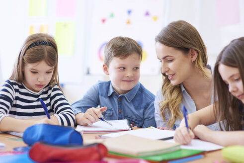 Der Lehrer hilft den Schülern bei ihren Aufgaben im Unterricht - ABIF00380