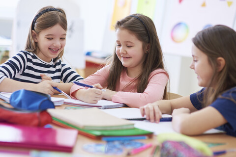 Happy schoolgirls working together in class stock photo