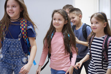 Smiling pupils on corridor leaving school - ABIF00382