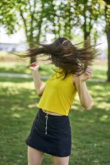 Junge Frau im Park, die ihr Haar wirft - BEF00059