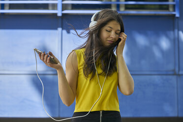 Porträt einer jungen Frau, die mit Kopfhörern und Mobiltelefon Musik hört - BEF00061