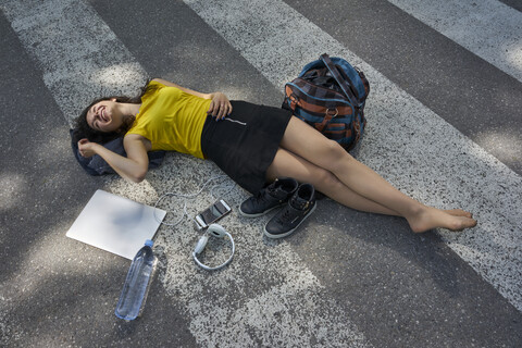 Young woman lying on zebra crossing taking a break stock photo