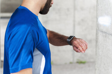Mann, der eine Pause vom Laufen macht und die Zeit auf einer Smartwatch überprüft - DIGF04251