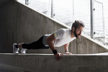 Man doing push-ups on concrete wall - DIGF04286