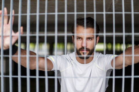 Portrait of confident athlete behind grid stock photo