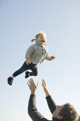 Weibliches Kleinkind, das von seinem Vater in die Luft geworfen wird, vor blauem Himmel - ISF01589