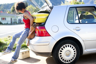 Woman struggling to push luggage into car boot - ISF01593