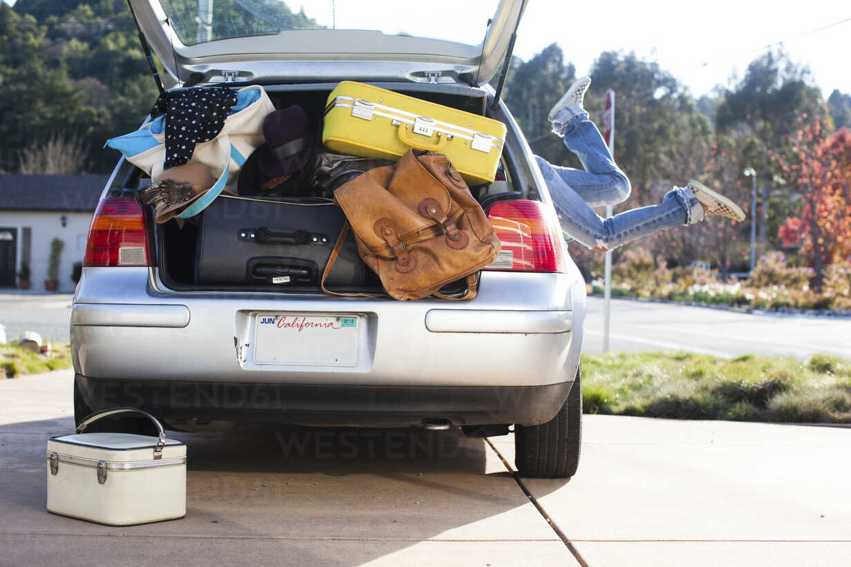 Car packed with luggage and legs of woman sticking out of car window stock photo