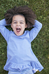 Portrait of young girl lying on grass, laughing, overhead view - ISF01610