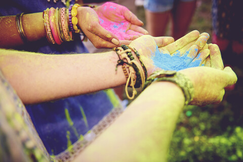 Pink and blue chalk cupped in young couples hands at festival stock photo