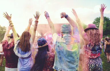 Rückansicht von jungen erwachsenen Freunden, die auf einem Festival tanzen und mit farbigem Kreidepulver werfen - ISF01654
