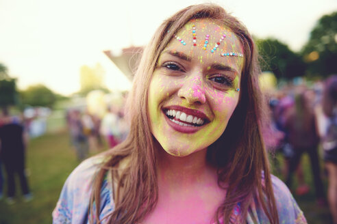 Porträt einer jungen Boho-Frau mit einem mit farbigem Kreidepulver bedeckten Gesicht auf einem Festival - ISF01657