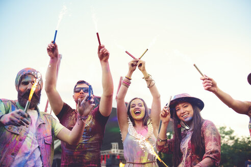 Junge Erwachsene, bedeckt mit farbigem Kreidepulver, tanzen mit Wunderkerzen auf einem Festival - ISF01660