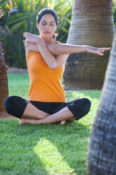 Woman sitting outdoors, stretching, meditating - CUF07732