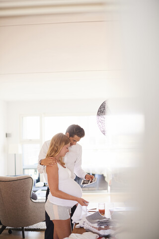 Pregnant couple looking at ultrasound pictures in living room stock photo