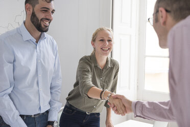 Businesswoman and man shaking hands at boardroom table - CUF07819