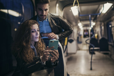 Couple using mobile phone in train, Florence, Italy - CUF07842