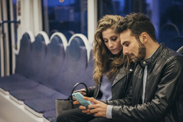 Couple using mobile phone in train, Florence, Italy - CUF07845