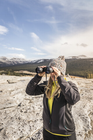 Frau schaut durch ein Fernglas, Yosemite National Park, Kalifornien, USA, lizenzfreies Stockfoto