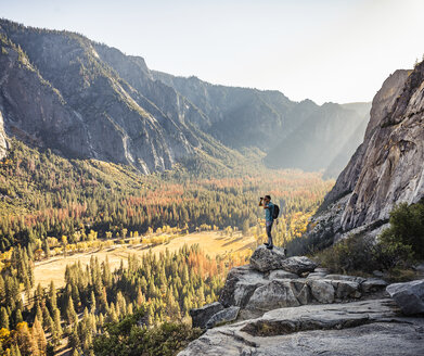 Mann auf einer Felskante, der durch ein Fernglas schaut, Yosemite National Park, Kalifornien, USA - CUF07877