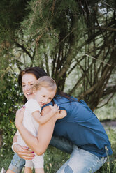 Mother hugging young daughter, outdoors - CUF07895