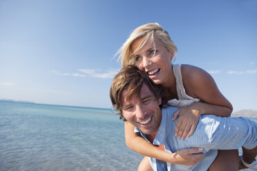 Couple playing piggyback ride by sea - CUF07941