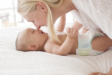 Mid erwachsene Frau Nase an Nase mit Baby Sohn auf dem Bett liegend - ISF01687