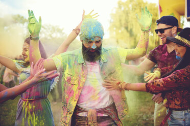 Young adult friends throwing coloured chalk powder and dancing at festival - ISF01772