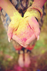 Waist down view of young boho woman with coloured chalk powder in cupped hands at festival - ISF01774