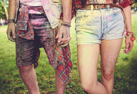 Waist down view of young couple covered in coloured chalk powder at festival stock photo