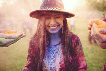 Hände bedecken junge Boho-Frau mit farbigem Kreidepulver auf Festival - ISF01778