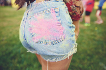 Ausschnitt aus den Jeans-Shorts einer jungen Frau mit rosa Kreide-Handabdruck auf dem Gesäß auf einem Festival - ISF01780