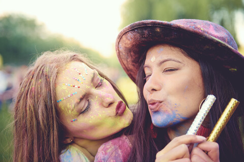 Porträt von zwei jungen Frauen, die mit farbigem Kreidepulver beschmiert sind und auf einem Fest die Lippen schürzen, lizenzfreies Stockfoto