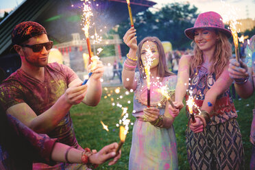 Junge Erwachsene, die mit farbigem Kreidepulver bedeckt sind und Wunderkerzen auf einem Fest halten - ISF01785