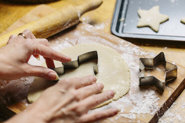 Mature woman pressing cookie cutter into dough, close-up - ISF01804