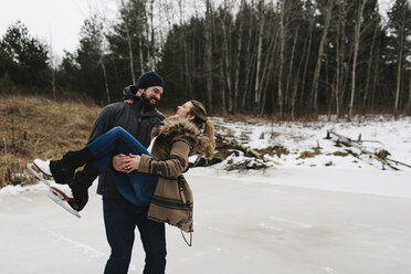 Man skating with woman in his arms, Whitby, Ontario, Canada - ISF01837