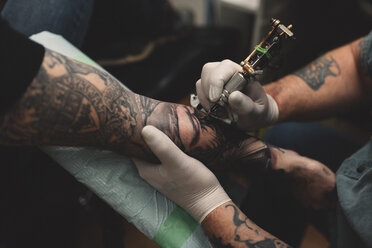 Tattooist tattooing young man's arm, close-up - ISF01850